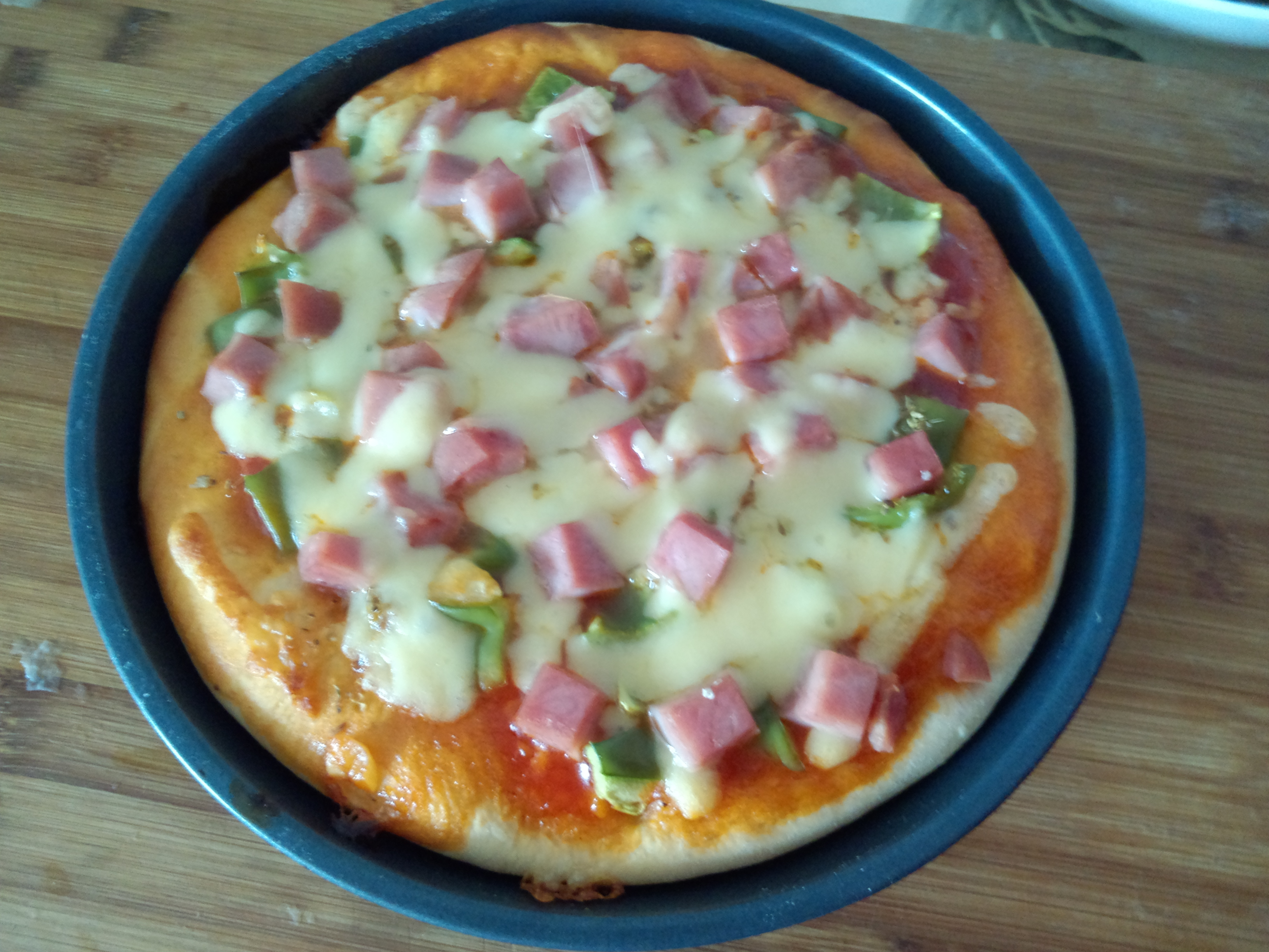 火腿青椒玉米披萨,青椒和玉米特别适合做披萨,再配以火腿,表面撒上